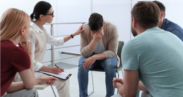 A man battling addiction being encouraged by a support group